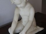 a statue of a child sitting on a marble slab