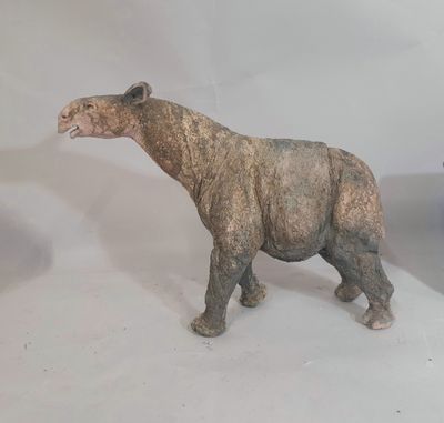 une statue représentant un rhinocéros debout à côté d'un vase de fleurs