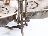 a silver plate with a bird on it on a stand