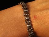 a woman ' s hand with a bracelet that has a diamond on it