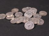 a pile of silver coins on a black surface