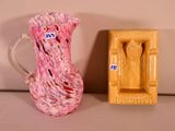 a pink glass pitcher next to a yellow soap dish