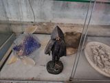 une petite figurine représentant un homme coiffé d'un chapeau, à côté d'un bol rempli de poissons