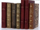 several old books are lined up in a row on a white surface