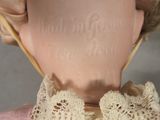 a close up of a doll wearing a pink dress and a bonnet