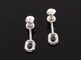a pair of silver earrings with black stones on a black surface