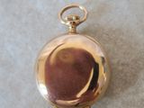 a small gold pocket watch on a white surface