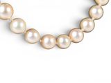 the pearl necklace has a gold clasp and a white pearl bead