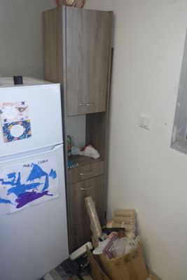 un réfrigérateur dans un coin d'une cuisine où il y a beaucoup de cartons par terre