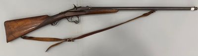 un vieux fusil accroché au mur à côté d'une paire de chaussures