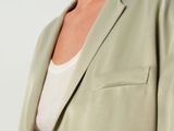 the model is wearing a light green blazer and a white top