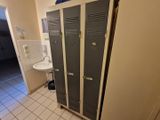 deux casiers dans une salle de bains équipée d'un lavabo et de toilettes