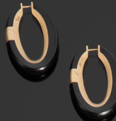 deux paires de boucles d'oreilles créoles noires et dorées posées sur un fond noir