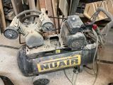 un petit compresseur d'air posé par terre à côté d'un tas de bois