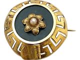 une broche en or ornée d'une perle au centre