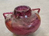 a purple vase sitting on a table with a red handle