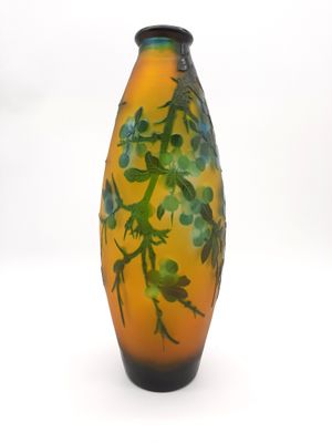 un vase jaune orné de feuilles vertes sur fond blanc