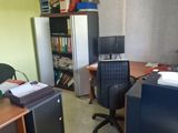 a desk with a computer and a refrigerator in a room