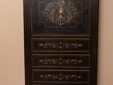 a black and gold chest of drawers in the corner of a room