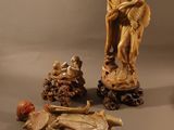 une statue représentant un homme assis sur un rocher, à côté d'autres statues
