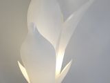 un gros plan d'une lampe blanche fixée au mur, à côté d'un autre mur