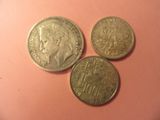 three coins sitting on top of a pink surface next to each other