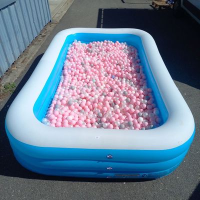 une piscine remplie de balles roses et blanches au milieu de la rue