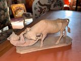 une figurine représentant une vache posée sur une table, avec un miroir en arrière-plan