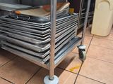 several trays of pans are stacked on a cart in a kitchen