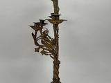 an antique brass candelab with three candles and a bird on it