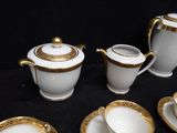 a white and gold tea set on a black table