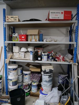 a room with a shelf full of paint and supplies