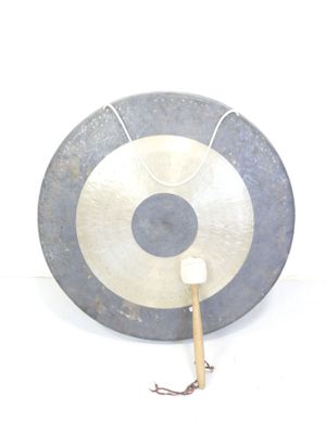 un grand disque métallique muni d'un manche en bois, sur fond blanc