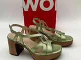 une paire de sandales vertes pour femme posées sur une surface blanche