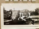 a black and white photo of a family in an old car
