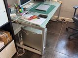 un bureau en verre sur lequel est posé un ordinateur