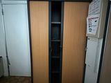 a cupboard in the corner of a room with a refrigerator
