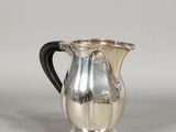 an image of a silver pitcher with a black handle sitting on a table