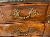 a wooden chest of drawers with gold decorations on it