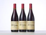 three bottles of red wine are lined up on a table