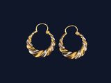 une paire de boucles d'oreilles créoles dorées et argentées sur fond noir