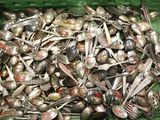un récipient vert rempli de cuillères et de fourchettes en argent
