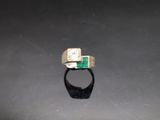 a close up of a ring with a green stone in it