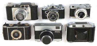 several old cameras are lined up in a row on a white surface