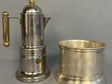 une cafetière en argent et une tasse en argent posées sur une table