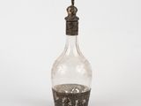 a glass bottle with a silver lid on a white surface