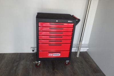 une armoire à outils rouge et noire posée sur un parquet en bois massif