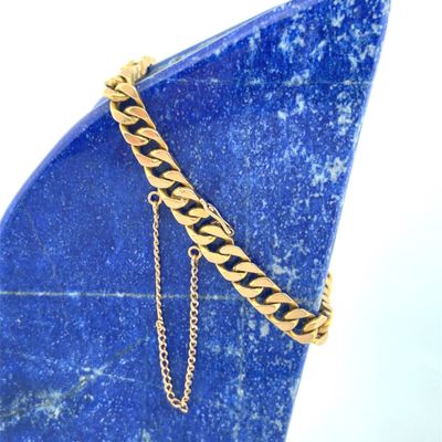 bracelet on a blue stone with a gold chain on it