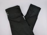 un gros plan sur une paire de leggings noirs posés sur une surface blanche