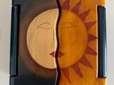 a wooden box with a sun and a face on it
